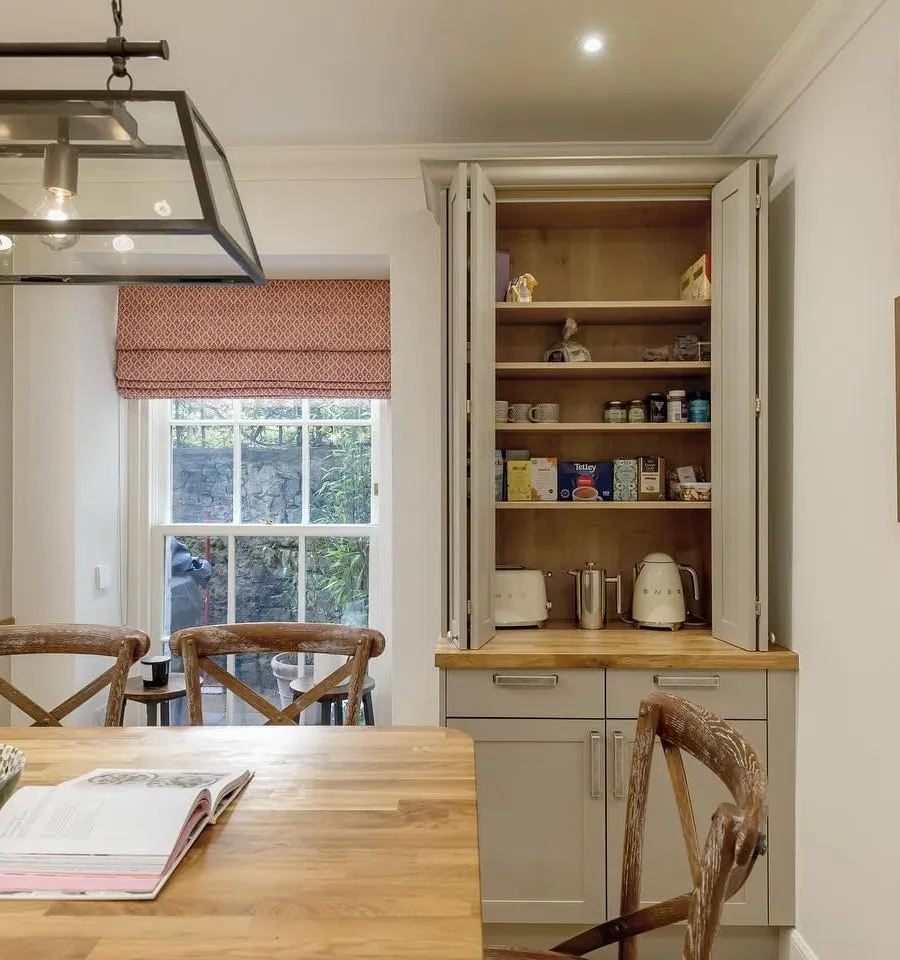 A renovated period kitchen with dark cabinetry and brass fittings